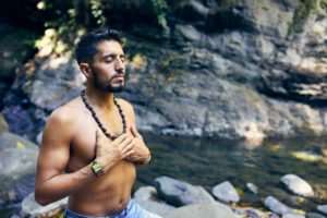 Homme d'origine Indienne au bord d'une rivière mains sur le coeur